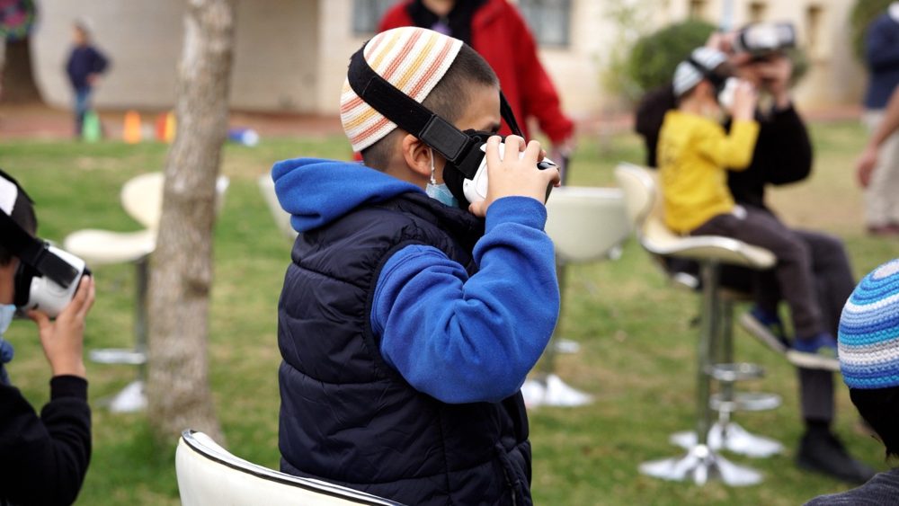 תלמיד חובש משקפי מציאות מדומה במהלך הפעילות בחוץ